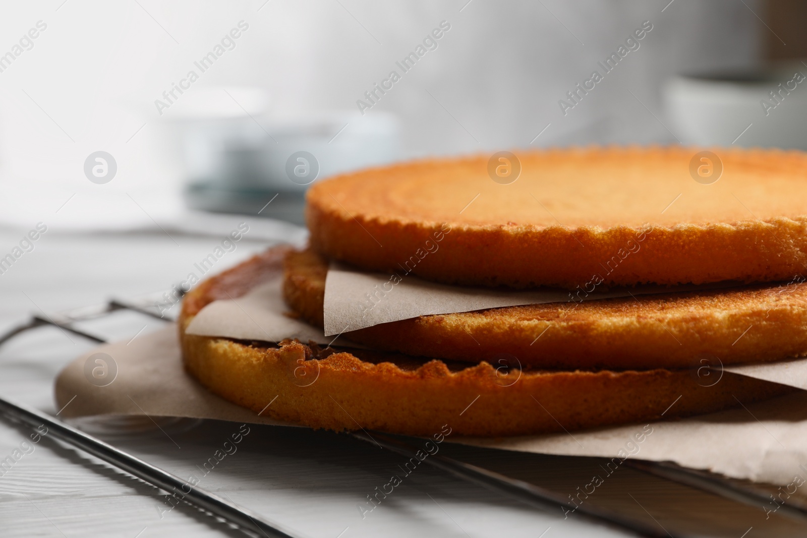 Photo of Delicious homemade sponge cakes with parchment on white wooden table, closeup