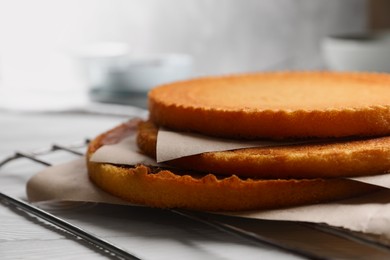 Delicious homemade sponge cakes with parchment on white wooden table, closeup