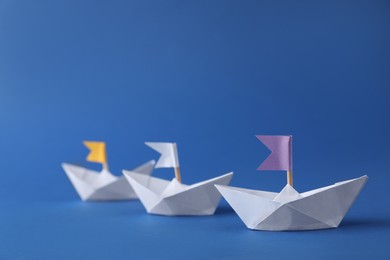 Photo of Handmade paper boats with flags on blue background. Origami art