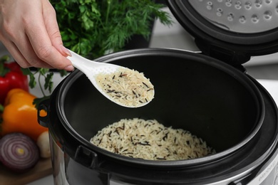 Photo of Woman filling multi cooker with rice, closeup