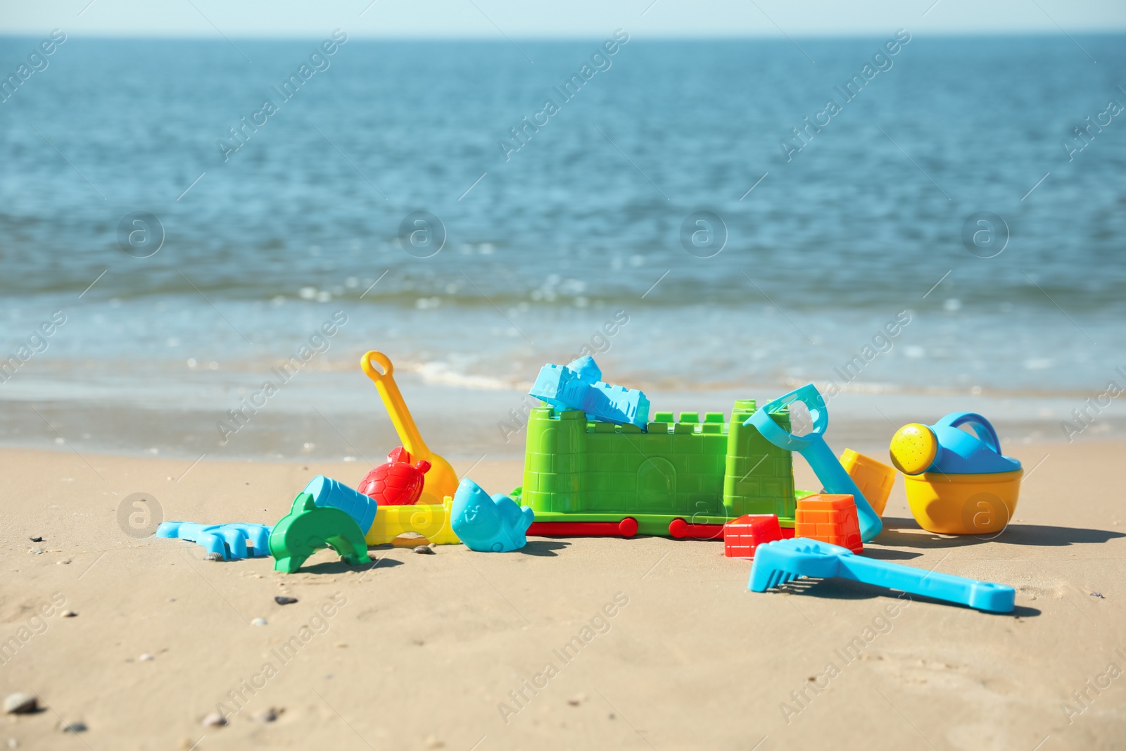 Photo of Different child plastic toys on sandy beach. Space for text