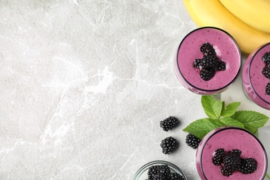 Delicious blackberry smoothie in glasses and ingredients on marble table, flat lay. Space for text