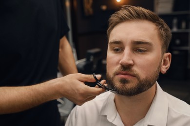 Professional hairdresser working with client in barbershop