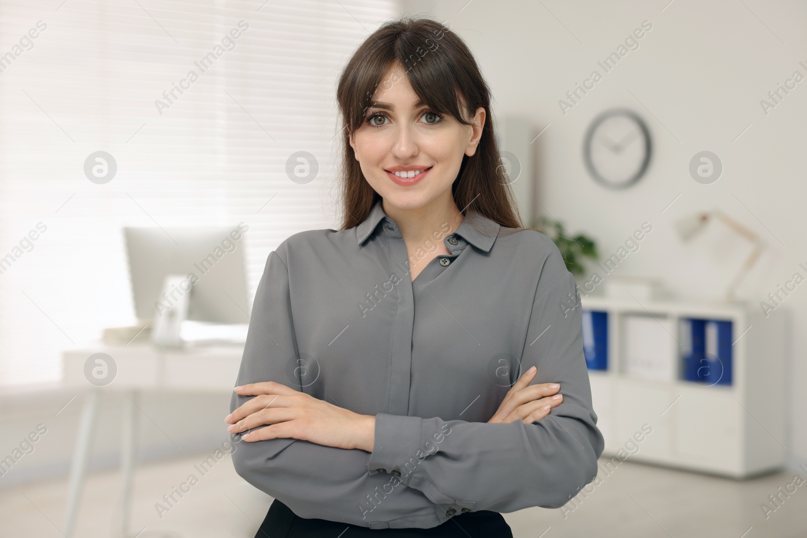 Photo of Portrait of smiling secretary with crossed arms in office