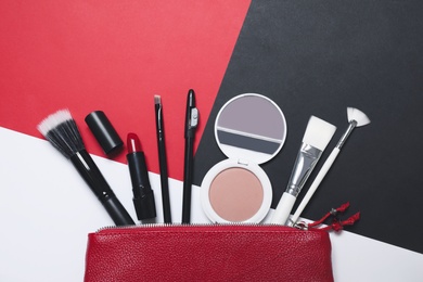 Different makeup products and bag on color background, flat lay