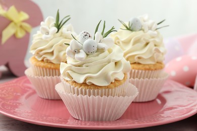 Photo of Tasty Easter cupcakes with vanilla cream on table, closeup