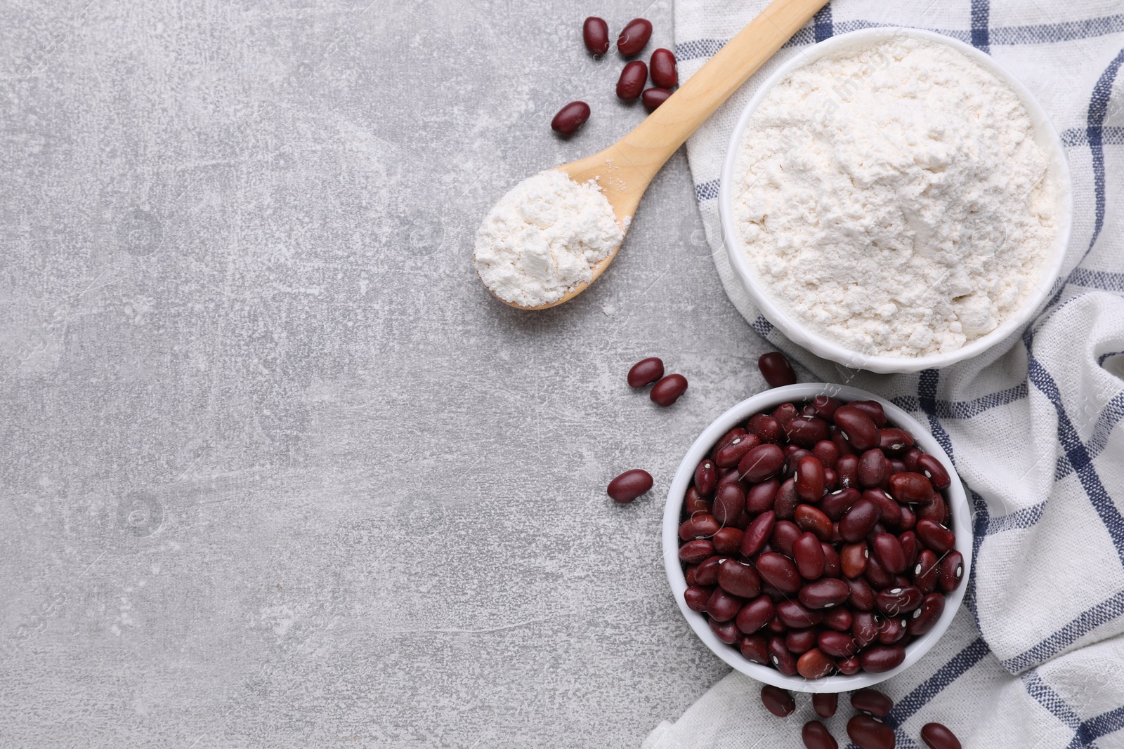 Photo of Kidney bean flour and seeds on light grey table, flat lay. Space for text