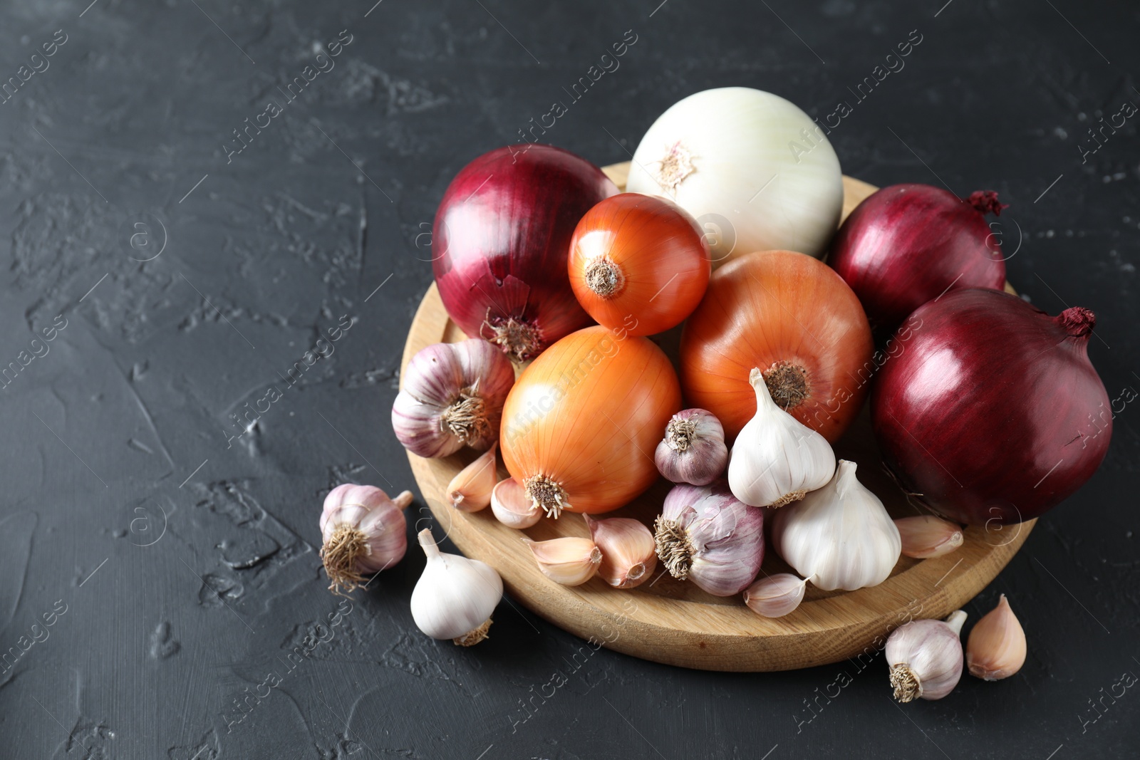 Photo of Fresh raw garlic and onions on black table. Space for text