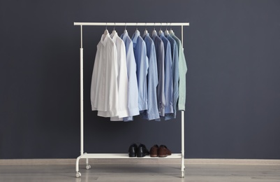 Photo of Wardrobe rack with men's clothes near dark wall