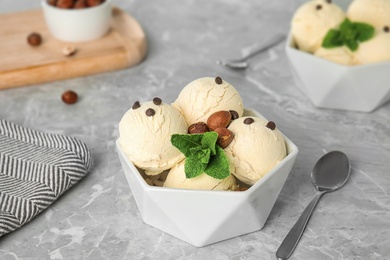 Photo of Delicious vanilla ice cream with mint, hazelnuts and chocolate chips served on table