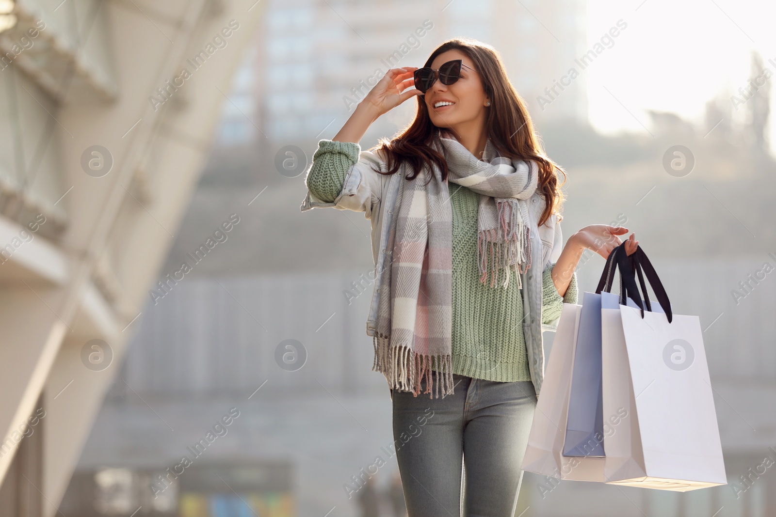 Photo of Beautiful young woman with shopping bags on city street