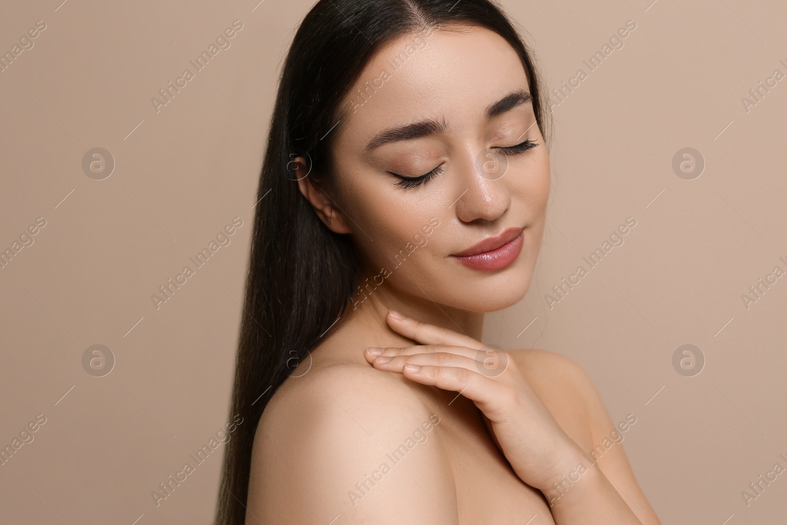 Photo of Portrait of beautiful young woman with elegant makeup on dark beige background