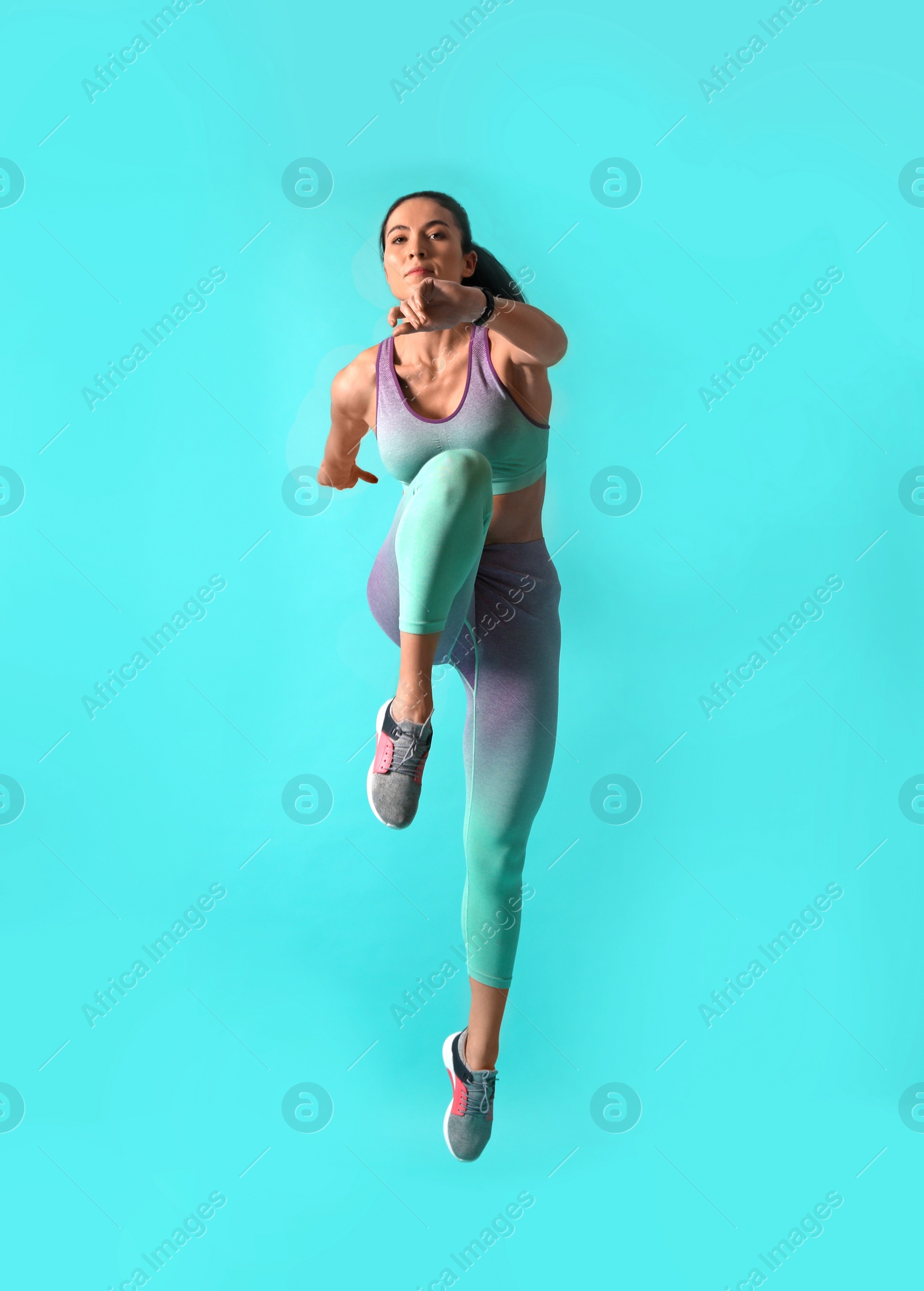 Photo of Athletic young woman running on turquoise background