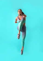 Photo of Athletic young woman running on turquoise background