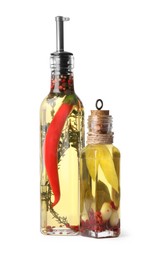 Photo of Glass bottles of cooking oil with spices and herbs on white background