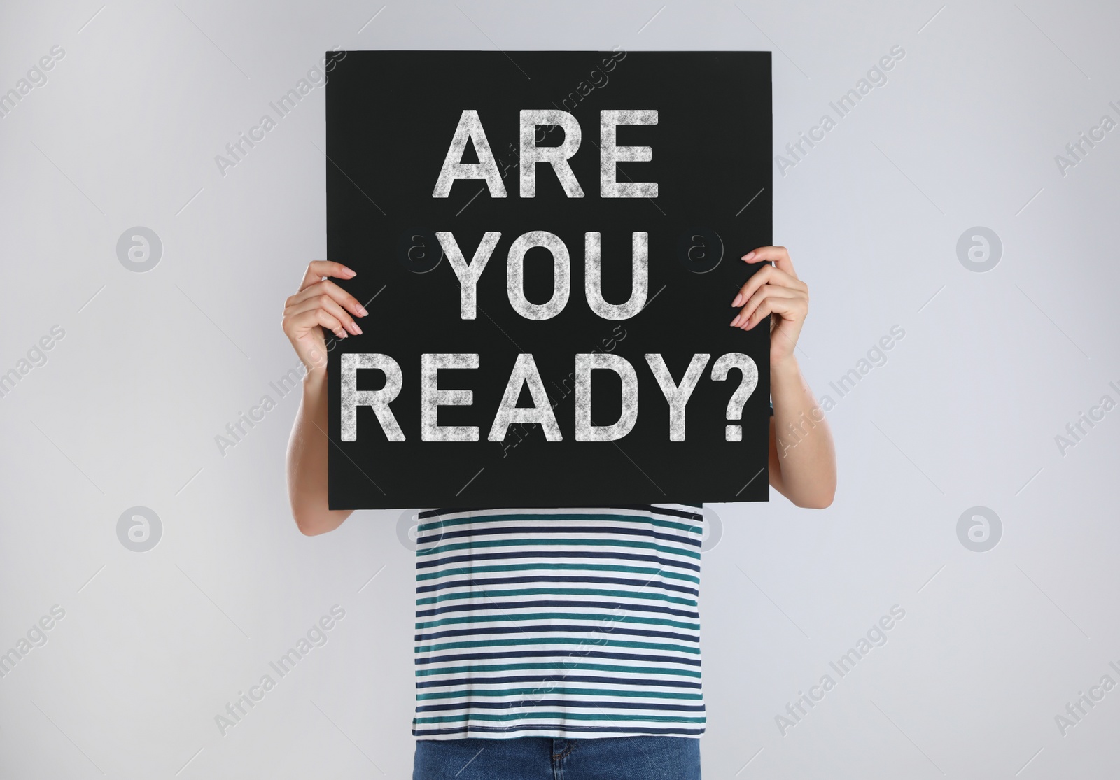 Image of Woman holding poster with text Are You Ready? on light grey background