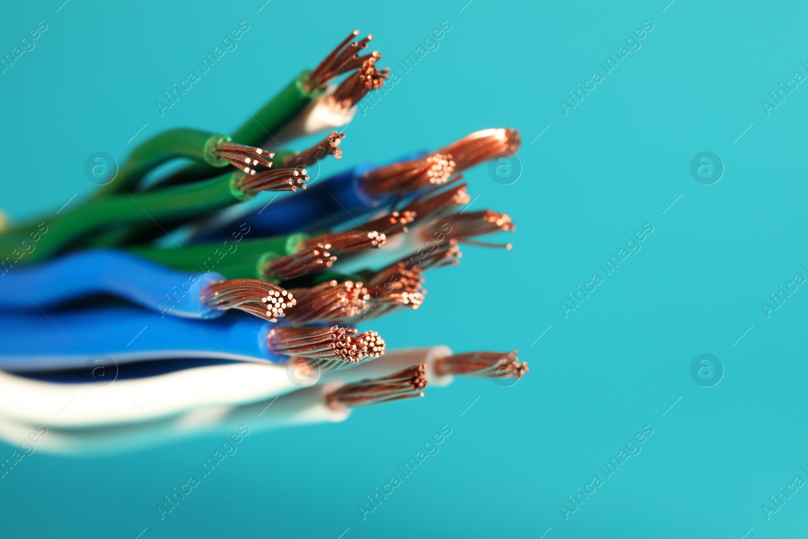 Photo of Electrical wires on light blue background, closeup. Space for text