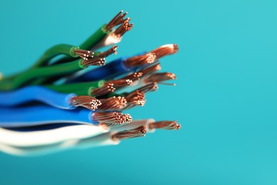 Photo of Electrical wires on light blue background, closeup. Space for text