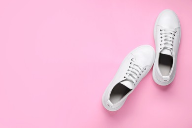 Photo of Pair of stylish white sneakers on pink background, top view. Space for text