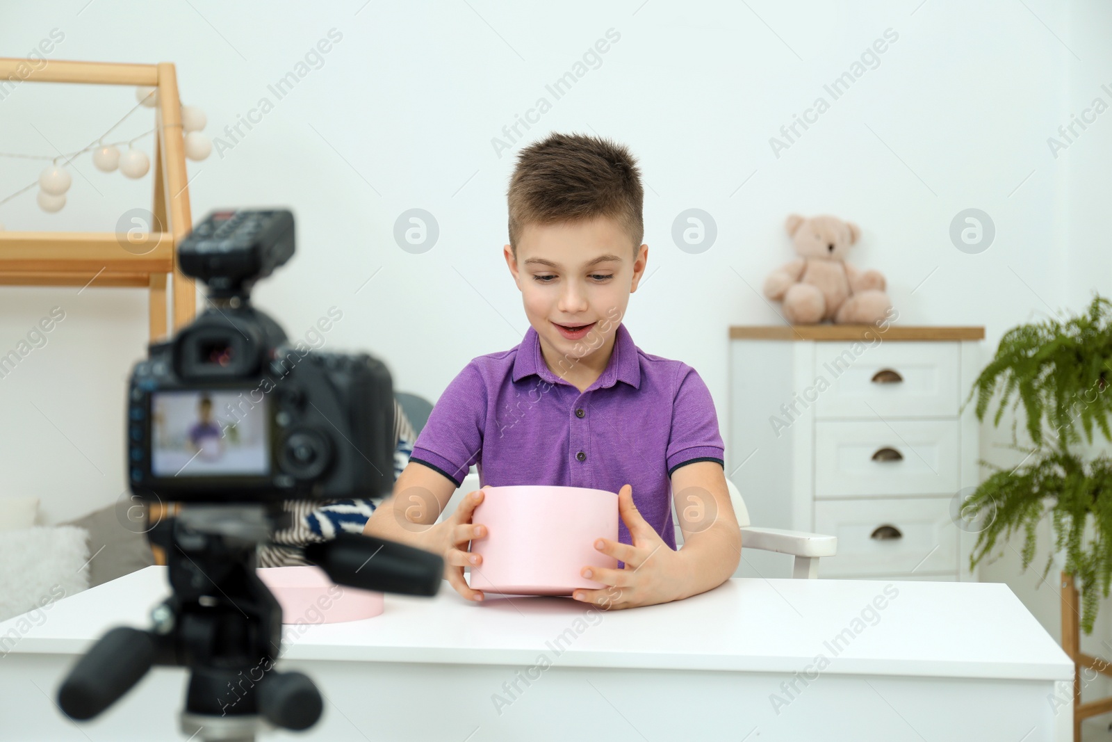 Photo of Cute little blogger with box recording video at home