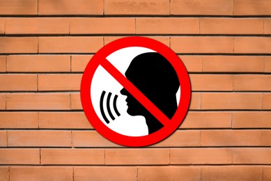 Image of Quiet Please. Prohibition sign with human head image red brick wall