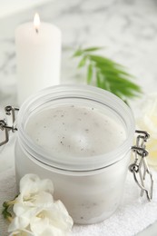 Photo of Jar of salt scrub, freesia flowers and towel on white marble table