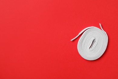 Photo of White shoelace on red background, top view. Space for text