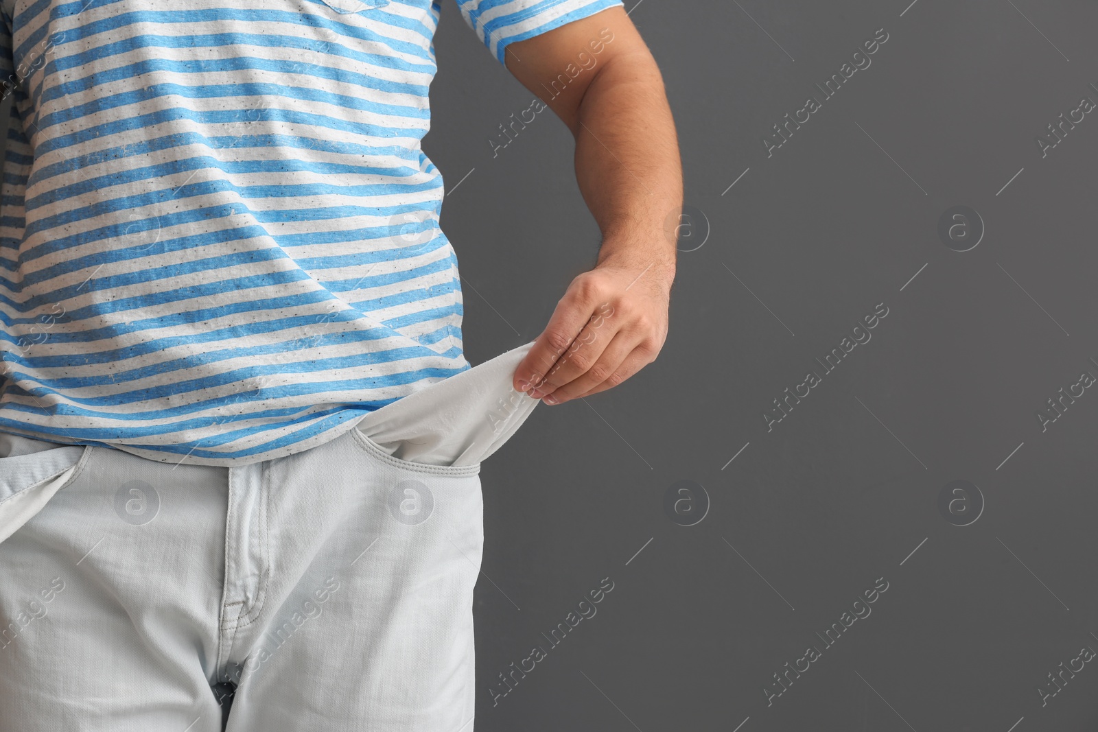 Photo of Man showing empty pocket on grey background, closeup. Space for text