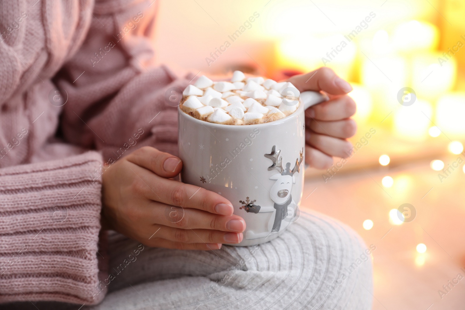 Photo of Woman holding cup of hot drink with marshmallows indoors, closeup. Magic Christmas atmosphere