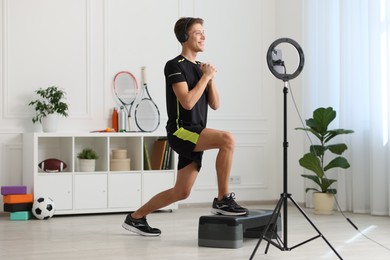 Smiling sports blogger streaming online fitness lesson with smartphone at home