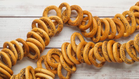 Photo of Bunch of delicious ring shaped Sushki (dry bagels) on white wooden table, top view