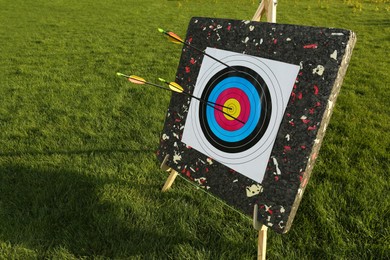 Photo of Arrows in archery target on green grass outdoors