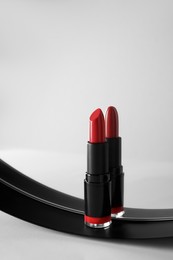 Stylish presentation of beautiful red lipstick and mirror on white table