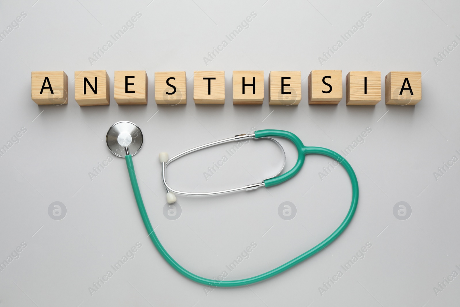 Photo of Wooden cubes with word Anesthesia and stethoscope on light grey background, flat lay