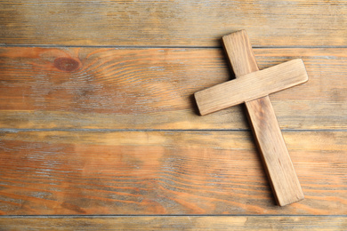Photo of Christian cross on wooden background, top view with space for text. Religion concept