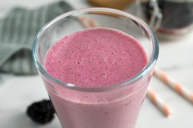 Glass of blackberry smoothie on white table, closeup