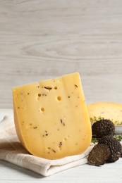 Photo of Delicious cheese, thyme and fresh black truffles on white wooden table. Space for text
