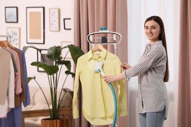 Woman steaming shirt on hanger at home