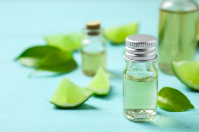 Photo of Lime essential oil and cut citrus fruits on light blue wooden table. Space for text