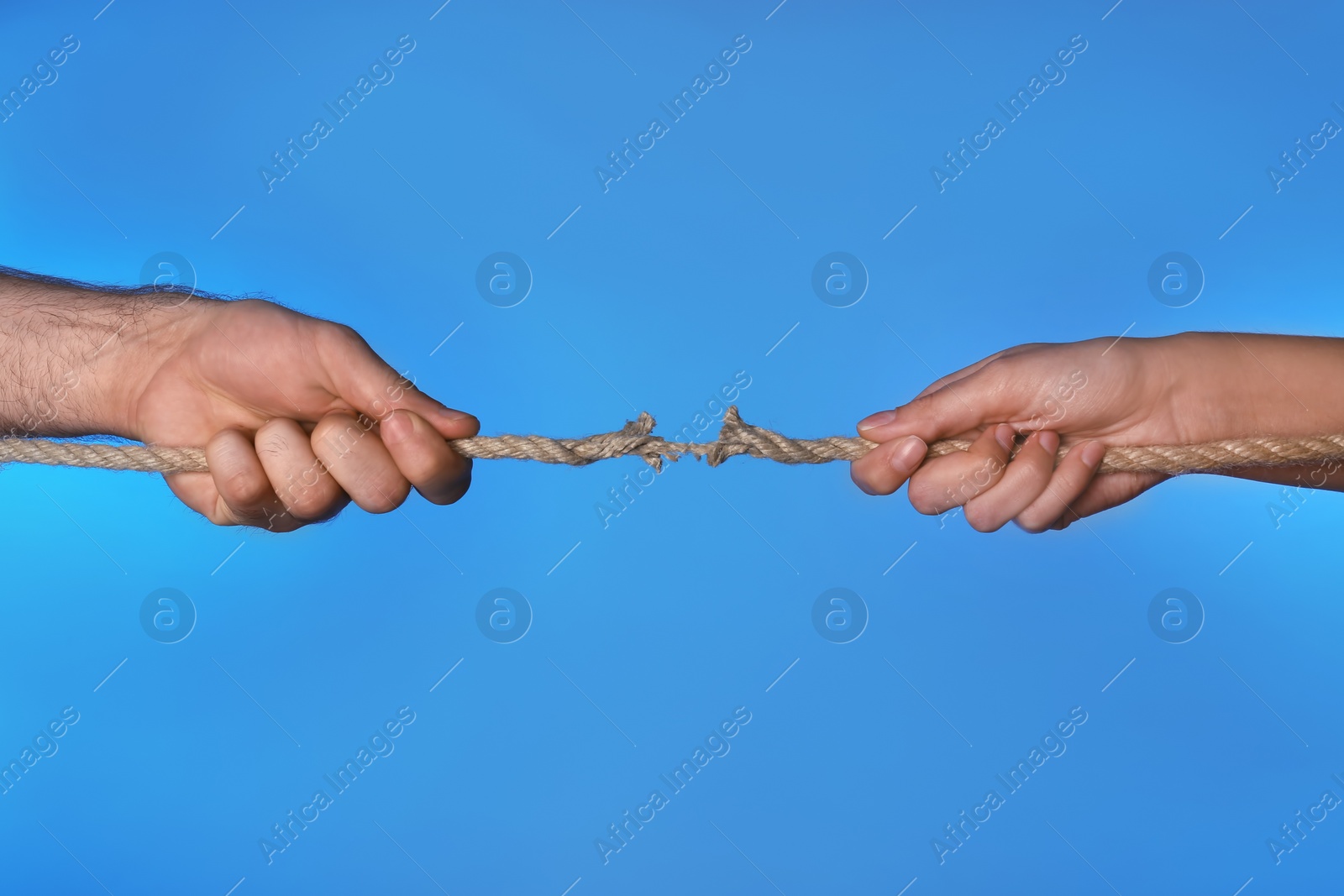 Photo of Woman and man pulling damaged rope on color background