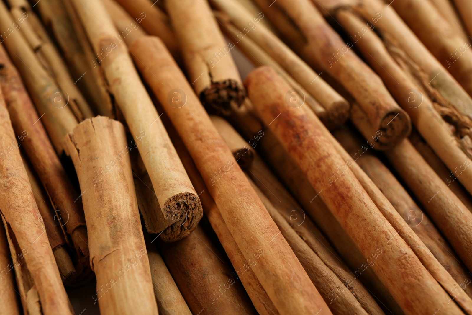 Photo of Aromatic cinnamon sticks as background, closeup view