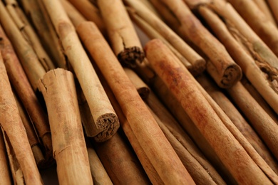 Photo of Aromatic cinnamon sticks as background, closeup view