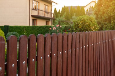 Photo of House and trees behind beautiful wooden fence outdoors