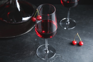 Photo of Delicious cherry wine with ripe juicy berries on grey table