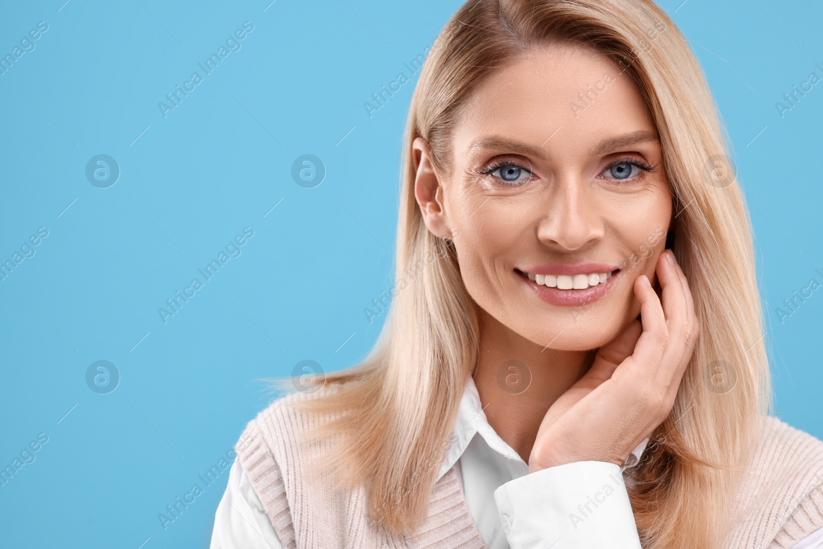 Photo of Portrait of smiling middle aged woman on light blue background. Space for text