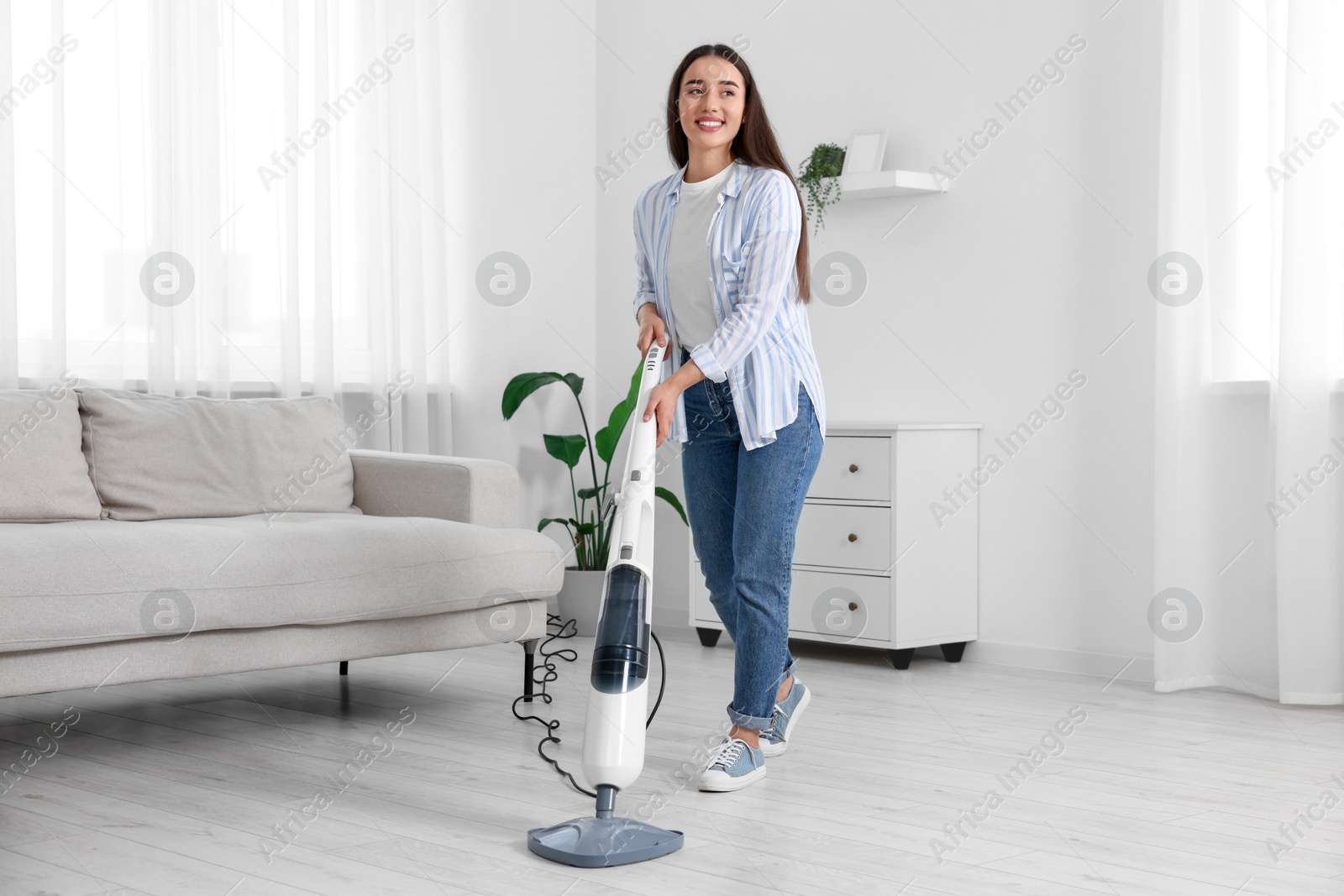 Photo of Happy woman cleaning floor with steam mop at home