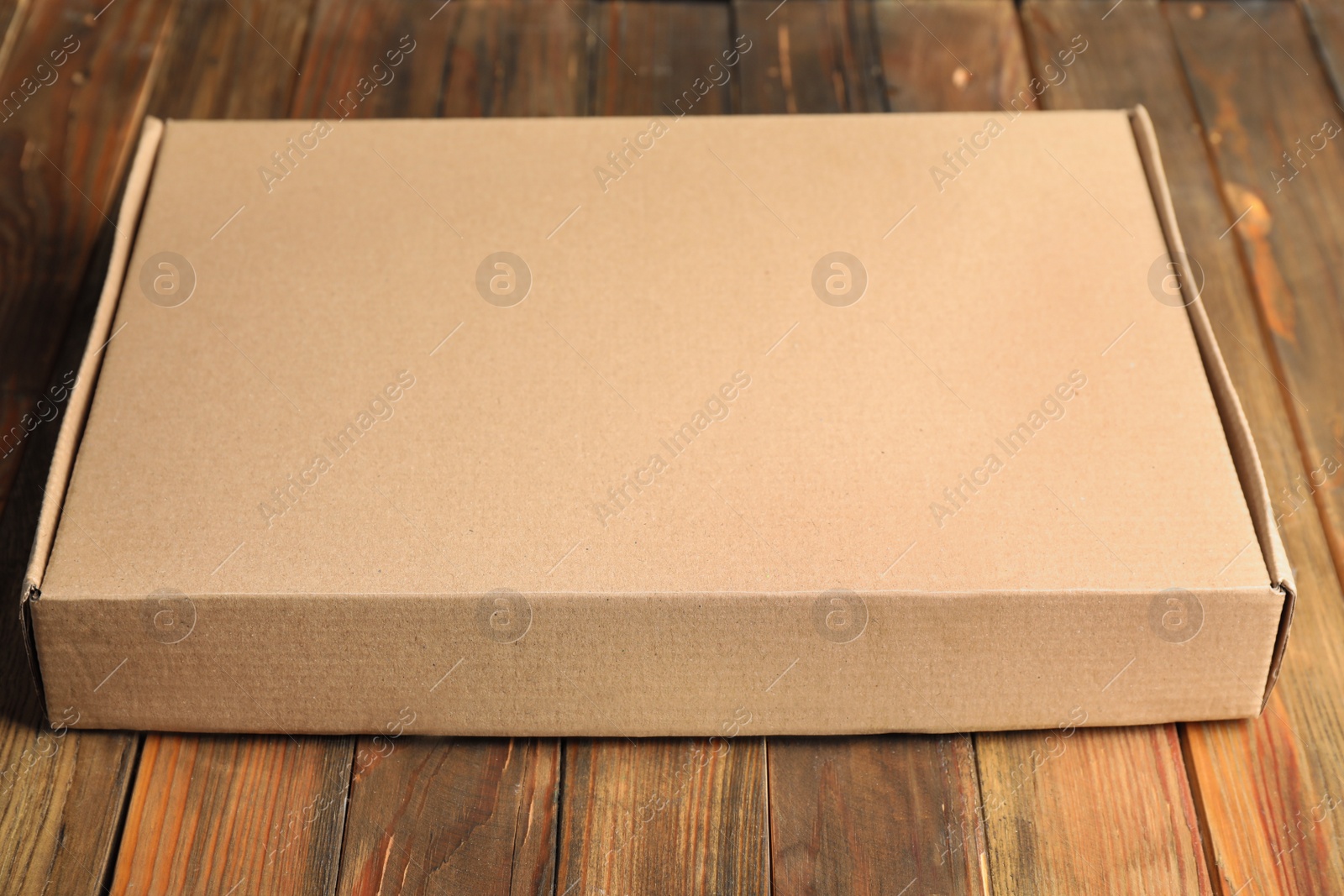 Photo of Closed cardboard box on brown wooden table