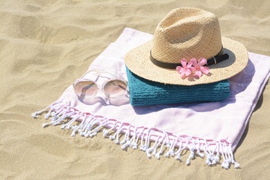 Photo of Stylish beach accessories and flowers on sand outdoors