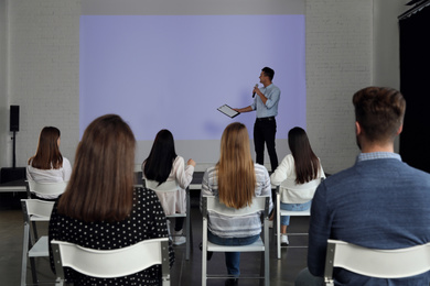 Photo of Male business trainer giving lecture in conference room with projection screen