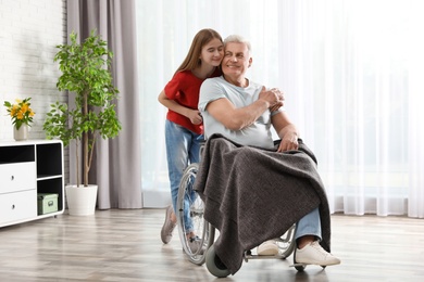 Teenage girl with grandfather in wheelchair at home